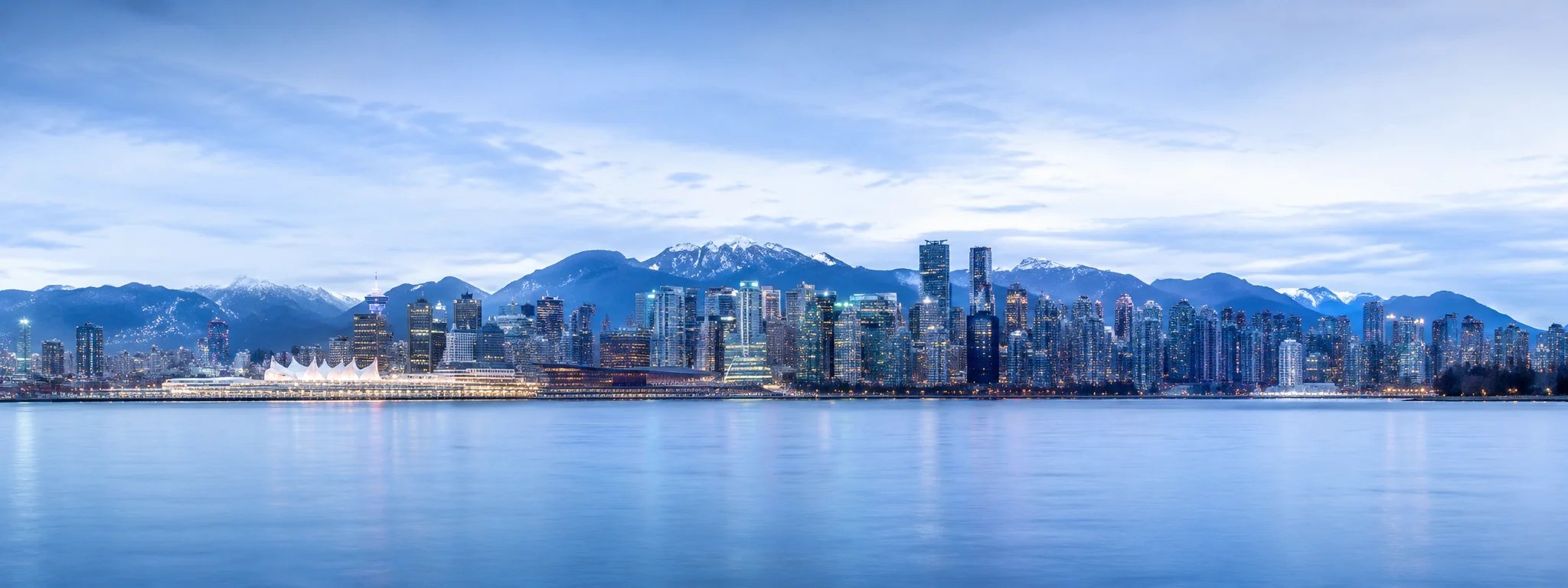 Vancouver skyline at blue hour seen across the water, mountains behind