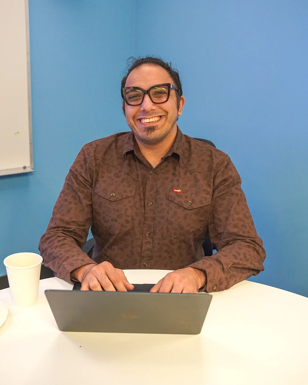 A participant smiling behind a laptop at the hackathon.